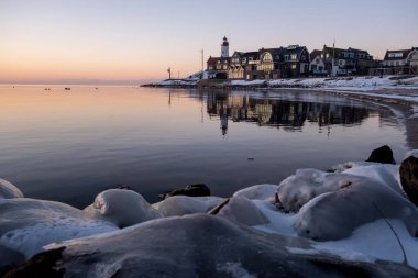 Urk 'ta kış aylarında hendek ve kumsalda Urk deniz fenerinin yanında kış boyunca kar, Urk Flevoland deniz fenerinde gün batımında
