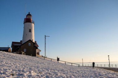 Urk 'ta kış aylarında hendek ve kumsalda Urk deniz fenerinin yanında kış boyunca kar, Urk Flevoland deniz fenerinde gün batımında