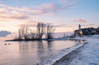 Urk 'ta kış aylarında hendek ve kumsalda Urk deniz fenerinin yanında kış boyunca kar, Urk Flevoland deniz fenerinde gün batımında