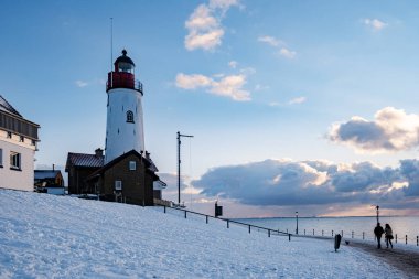 Urk 'ta kış aylarında hendek ve kumsalda Urk deniz fenerinin yanında kış boyunca kar, Urk Flevoland deniz fenerinde gün batımında