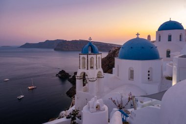 Oia köyü Santorini 'nin mavi kubbeleri ve beyaz boyalı evi günbatımında Santorini adasında Yunanistan' da