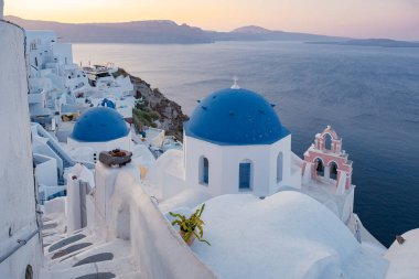 Oia köyü Santorini 'nin mavi kubbeleri ve beyaz boyalı evi günbatımında Santorini adasında Yunanistan' da