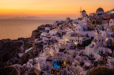 Oia köyü Santorini 'nin mavi kubbeleri ve beyaz boyalı evi günbatımında Santorini adasında Yunanistan' da