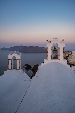 Oia köyü Santorini 'nin mavi kubbeleri ve beyaz boyalı evi günbatımında Santorini adasında Yunanistan' da