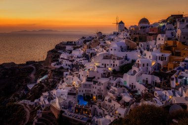 Oia köyü Santorini 'nin mavi kubbeleri ve beyaz boyalı evi günbatımında Santorini adasında Yunanistan' da