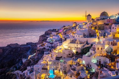 Oia köyü Santorini 'nin mavi kubbeleri ve beyaz boyalı evi günbatımında Santorini adasında Yunanistan' da