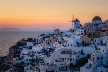 Oia köyü Santorini 'nin mavi kubbeleri ve beyaz boyalı evi günbatımında Santorini adasında Yunanistan' da