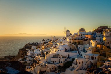 Oia köyü Santorini 'nin mavi kubbeleri ve beyaz boyalı evi günbatımında Santorini adasında Yunanistan' da