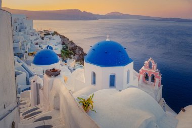 Oia köyü Santorini 'nin mavi kubbeleri ve beyaz boyalı evi günbatımında Santorini adasında Yunanistan' da