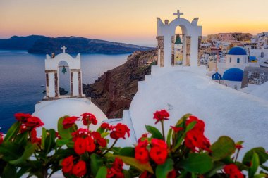 Oia köyü Santorini 'nin mavi kubbeleri ve beyaz boyalı evi günbatımında Santorini adasında Yunanistan' da