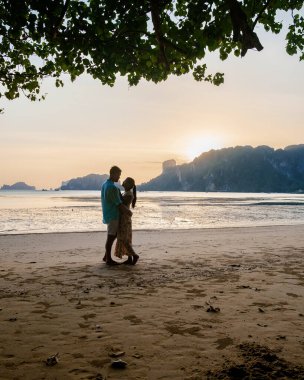 Çiftler sahilde gün batımını, Eropean erkeği ve Asyalı kadın gün batımını Krabi Tayland sahilinde seyrediyor.