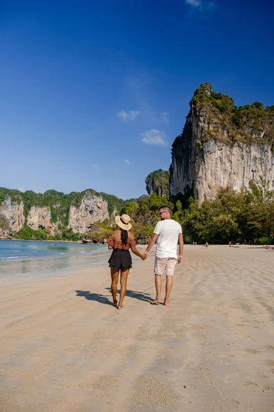Couple mid age on tropical beach in Thailand, tourist walking on a white tropical beach, Railay beach with on the background lontail boat drop off tourist — Stock Photo, Image