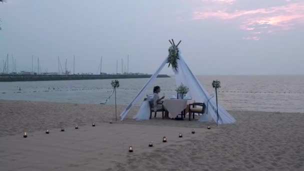 Mulher ter jantar romântico com luzes de vela na praia na Tailândia, homens europeus e mulher asiática jantar na praia Valentim conceito — Vídeo de Stock