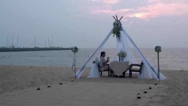 Frau beim romantischen Abendessen mit Kerzenschein am Strand in Thailand, europäische Männer und asiatische Frauen beim Abendessen am Strand Valentinskonzept — Stockvideo