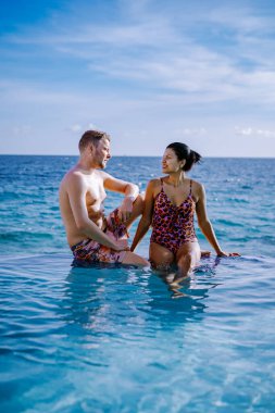 Rahatlatıcı yaz plajı, güneşlenme güvertesi ve sahilde palmiye ağaçları ve Curacao lüks evindeki panoramik deniz manzaralı özel yüzme havuzu.