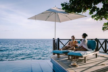 Rahatlatıcı yaz plajı, güneşlenme güvertesi ve sahilde palmiye ağaçları ve Curacao lüks evindeki panoramik deniz manzaralı özel yüzme havuzu.