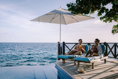 Rahatlatıcı yaz plajı, güneşlenme güvertesi ve sahilde palmiye ağaçları ve Curacao lüks evindeki panoramik deniz manzaralı özel yüzme havuzu.