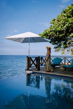 Rahatlatıcı yaz plajı, güneşlenme güvertesi ve sahilde palmiye ağaçları ve Curacao lüks evindeki panoramik deniz manzaralı özel yüzme havuzu.