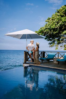 Rahatlatıcı yaz plajı, güneşlenme güvertesi ve sahilde palmiye ağaçları ve Curacao lüks evindeki panoramik deniz manzaralı özel yüzme havuzu.