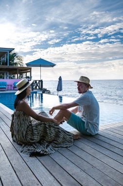 Rahatlatıcı yaz plajı, güneşlenme güvertesi ve sahilde palmiye ağaçları ve Curacao lüks evindeki panoramik deniz manzaralı özel yüzme havuzu.