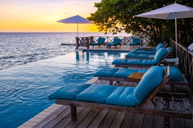 Rahatlatıcı yaz plajı, güneşlenme güvertesi ve sahilde palmiye ağaçları ve Curacao lüks evindeki panoramik deniz manzaralı özel yüzme havuzu.