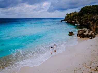 Curacao 'daki Playa Kalki' de plaj ve iskele, gökyüzünden gelen tropik plaj insansız hava aracı manzaralı palmiye ağacı olan plaj manzaralı.