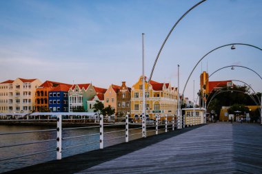 Curacao Willemstad, renkli Willemstad şehrinde gün batımı. İnsanlar Flooten Köprüsü 'nde yürüyor.