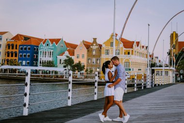 Curacao Willemstad, renkli Willemstad şehrinde gün batımı. İnsanlar Flooten Köprüsü 'nde yürüyor.