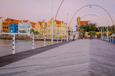 Curacao Willemstad, renkli Willemstad şehrinde gün batımı. İnsanlar Flooten Köprüsü 'nde yürüyor.