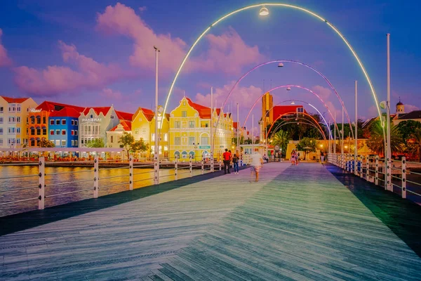 Curacao Willemstad, renkli Willemstad şehrinde gün batımı. İnsanlar Flooten Köprüsü 'nde yürüyor.