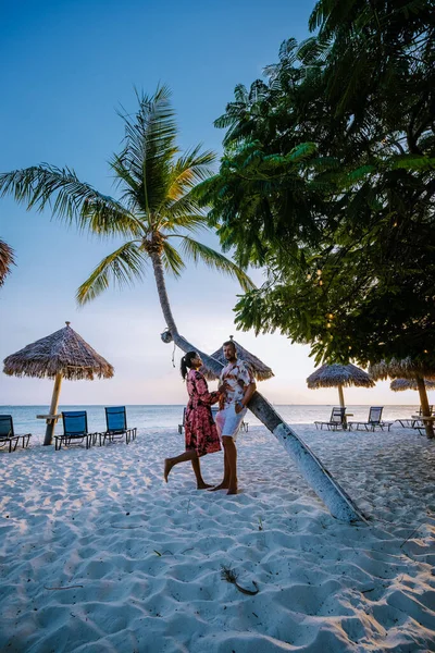 Palm beach Aruba, Increíble playa tropical con palmeras que ingresan al océano contra el océano azul, arena dorada y cielo azul — Foto de Stock