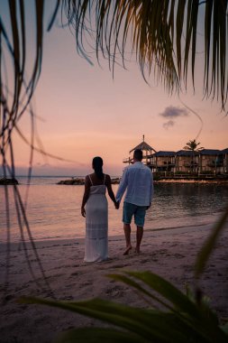 Günbatımında Curacao sahilinde bir çift, erkek ve kadın Curacao tropik plajında gün batımını izliyor.