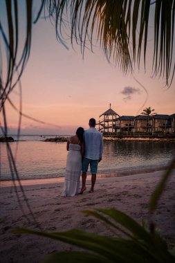 Günbatımında Curacao sahilinde bir çift, erkek ve kadın Curacao tropik plajında gün batımını izliyor.
