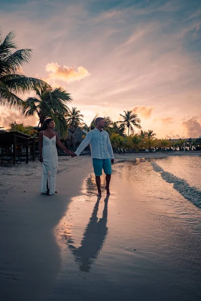 夕暮れ時のキュラソー島のビーチでカップル、男性と女性はキュラソー島の熱帯ビーチで夕日を見ます — ストック写真