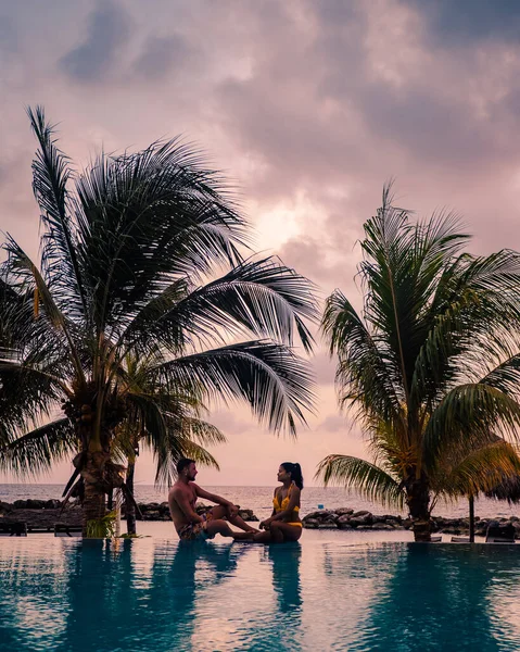 Casal na praia de Curaçao durante o pôr do sol, homens e mulheres assistindo ao pôr do sol na praia tropical de Curaçao — Fotografia de Stock