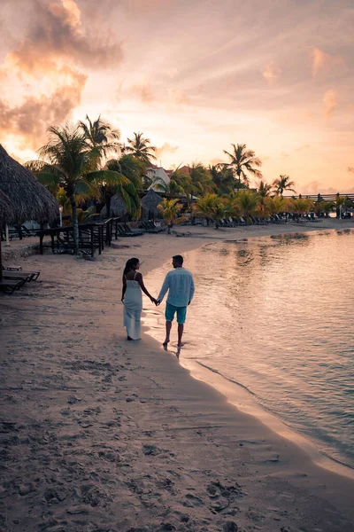 Pareja en la playa de Curazao durante la puesta del sol, hombres y mujeres observando la puesta del sol en la playa tropical de Curazao — Foto de Stock