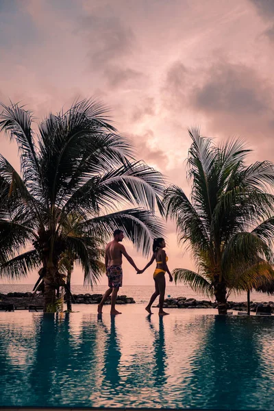 Pár Curacao strandján naplementekor, férfiak és nők nézik a naplementét Curacao trópusi strandján. — Stock Fotó