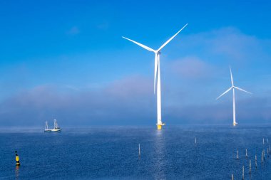 Bulutları ve mavi gökyüzü olan off-shore yel değirmeni parkı, okyanus drone parkı rüzgar türbini Flevoland Hollanda Ijsselmeer ile hava manzaralı