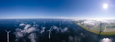 Bulutları ve mavi gökyüzü olan off-shore yel değirmeni parkı, okyanus drone parkı rüzgar türbini Flevoland Hollanda Ijsselmeer ile hava manzaralı