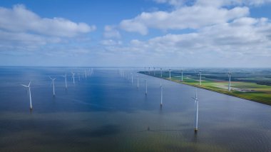 Bulutları ve mavi gökyüzü olan off-shore yel değirmeni parkı, okyanus drone parkı rüzgar türbini Flevoland Hollanda Ijsselmeer ile hava manzaralı