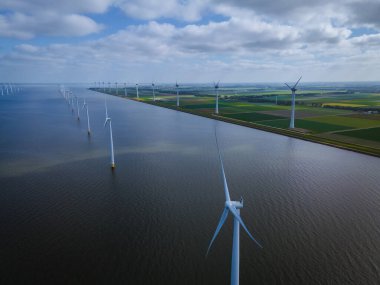 Bulutları ve mavi gökyüzü olan off-shore yel değirmeni parkı, okyanus drone parkı rüzgar türbini Flevoland Hollanda Ijsselmeer ile hava manzaralı