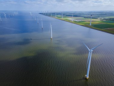 Bulutları ve mavi gökyüzü olan off-shore yel değirmeni parkı, okyanus drone parkı rüzgar türbini Flevoland Hollanda Ijsselmeer ile hava manzaralı