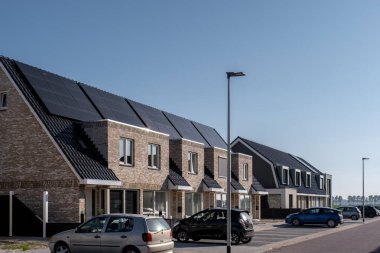 Güneşli bir gökyüzüne bağlı güneş panelleri olan yeni evler inşa edin. Siyah güneş panelleri olan yeni binaları kapatın. Zonnepanelen, Zonne enerjisi, Çevirisi: Güneş paneli, Güneş Enerjisi