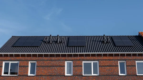 Case di nuova costruzione con pannelli solari attaccati sul tetto contro un cielo soleggiato Close up di nuovo edificio con pannelli solari neri. Zonnepanelen, Zonne energie, Traduzione: Pannello solare,, Energia solare — Foto Stock