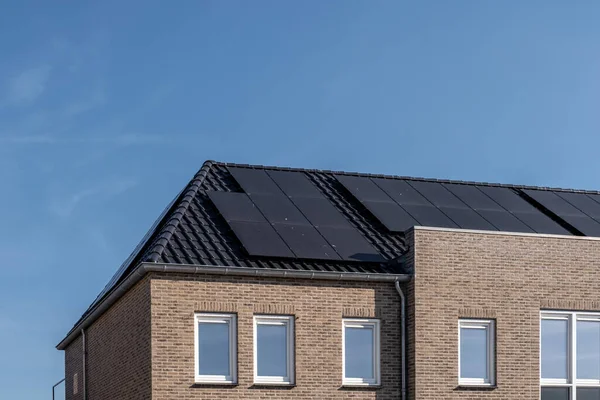 Nybyggda hus med solpaneler fästa på taket mot en solig himmel Närbild av ny byggnad med svarta solpaneler. Zonnepanelen, Zonne energie, Översättning: Solpanel,, Sun Energy — Stockfoto