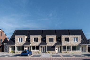 Güneşli bir gökyüzüne bağlı güneş panelleri olan yeni evler inşa edin. Siyah güneş panelleri olan yeni binaları kapatın. Zonnepanelen, Zonne enerjisi, Çevirisi: Güneş paneli, Güneş Enerjisi