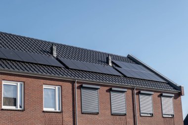 Güneşli bir gökyüzüne bağlı güneş panelleri olan yeni evler inşa edin. Siyah güneş panelleri olan yeni binaları kapatın. Zonnepanelen, Zonne enerjisi, Çevirisi: Güneş paneli, Güneş Enerjisi