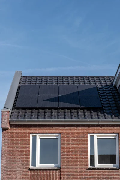 Nybyggda hus med solpaneler fästa på taket mot en solig himmel Närbild av ny byggnad med svarta solpaneler. Zonnepanelen, Zonne energie, Översättning: Solpanel,, Sun Energy — Stockfoto