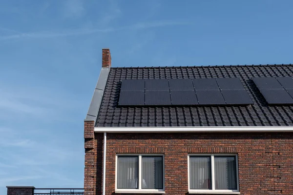 Nybyggda hus med solpaneler fästa på taket mot en solig himmel Närbild av ny byggnad med svarta solpaneler. Zonnepanelen, Zonne energie, Översättning: Solpanel,, Sun Energy — Stockfoto