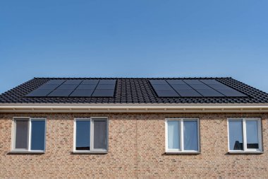 Güneşli bir gökyüzüne bağlı güneş panelleri olan yeni evler inşa edin. Siyah güneş panelleri olan yeni binaları kapatın. Zonnepanelen, Zonne enerjisi, Çevirisi: Güneş paneli, Güneş Enerjisi